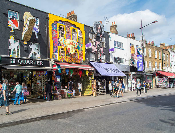 Camden Town Shops London, UK: July 26, 2016: Tourists walk past the colourful and funky shops on the main street in Camden. Camden Town, district of Inner London, one of the most popular places in London among locals and tourists. camden market stock pictures, royalty-free photos & images
