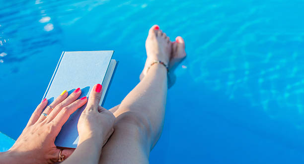 istock Girl reading by the swimming pool 584472270