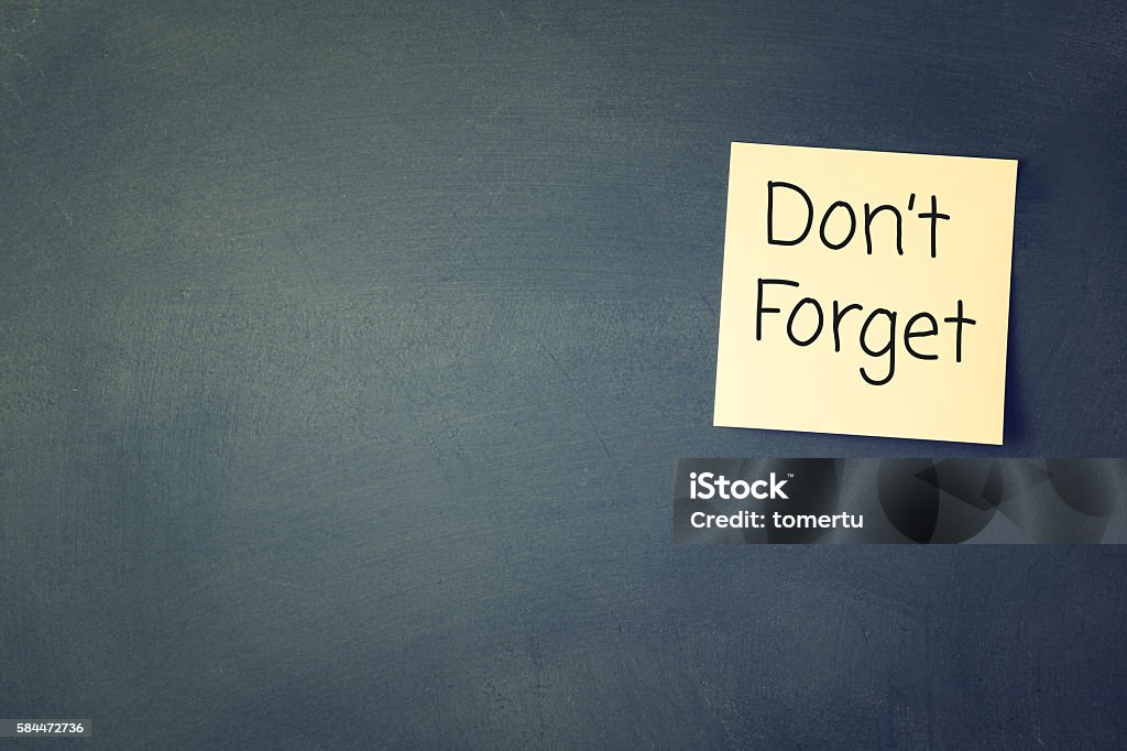 don't forget reminder, written on sticky memo don't forget reminder, written on sticky memo attached to blackboard Reminder Stock Photo