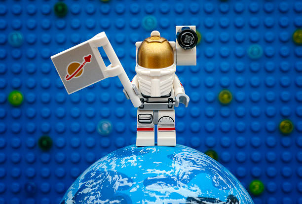 Tambov, Russian Federation - July 06, 2016 Lego spaceman minifigure with flag stay on planet against Lego blue baseplate with stars. Studio shot.