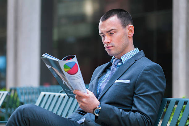 Businessman reading magazine stock photo