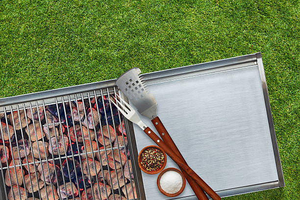 BBQ Grill Glowing Charcoal Briquettes Salt Pepper Utensils Grass Background Grill with glowing charcoal briquettes with salt pepper and grilling utensils outdoors on lawn tailgate party photos stock pictures, royalty-free photos & images
