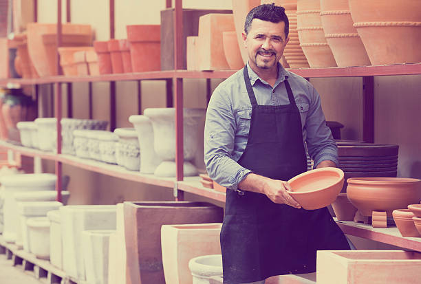 istock man potter holding ceramic vessels in atelier 584477756