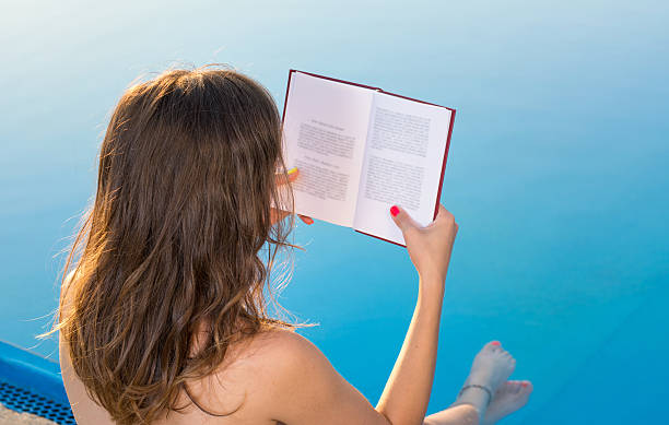 istock Girl reading by the swimming pool 584477808
