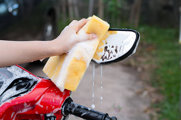 istock Female hand with  yellow sponge  washing a motorcycle. 584478044