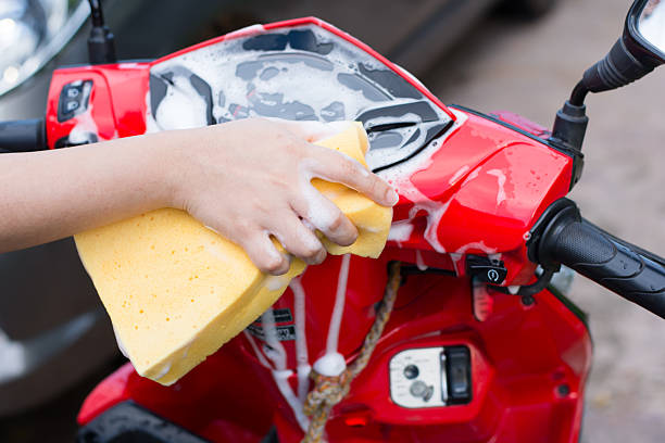 istock Female hand with  yellow sponge  washing a motorcycle. 584478192