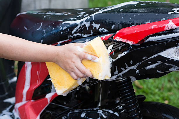 Female hand with  yellow sponge  washing a motorcycle. stock photo