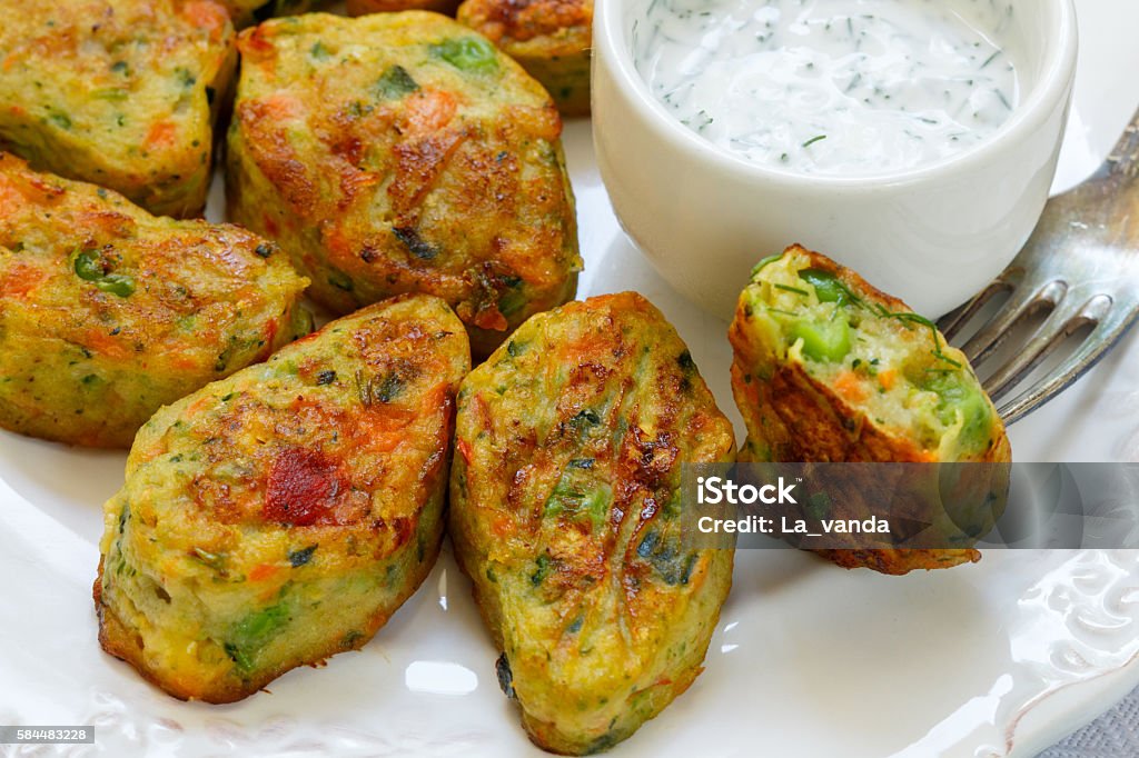 Healthy vegetarian potato patties Healthy vegetarian potato patties with carrots, broccoli, bell pepper, green peas and onions with sour cream sauce with dill and Basil. Selective focus Appetizer Stock Photo