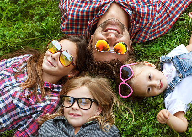 istock Dad and his 3 daughters lie on the grass happy. 584486450