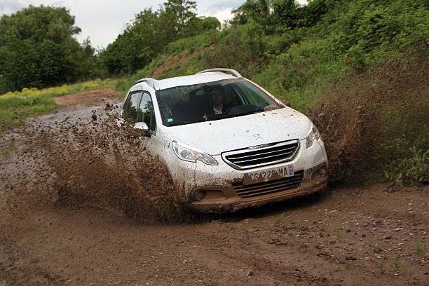 Paris, France - May 15th, 2013: Peugeot 2008 driving on the muddy road during the test drive. The 2008 model is one of the most popular crossover vehicles in Europe.