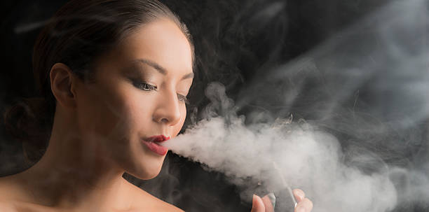istock Woman Smoking an E-Cigarette with vapor 584491330