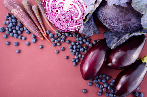 Purple fruits and vegetables thay contain Anthocynins, found in the Okinawan diet, that maintain healthy blood vessels and promote longevity, overhead with copy space.