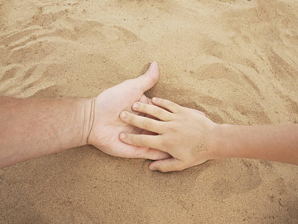 istock Father and son hands on sand. Close up 584493346