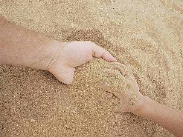 istock Father and son hands on sand. Close up 584493376
