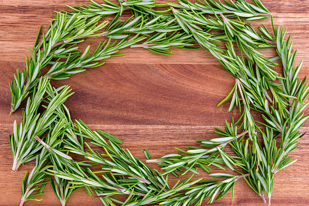 Sprigs of rosemary lined up in a circle on a wood cutting board