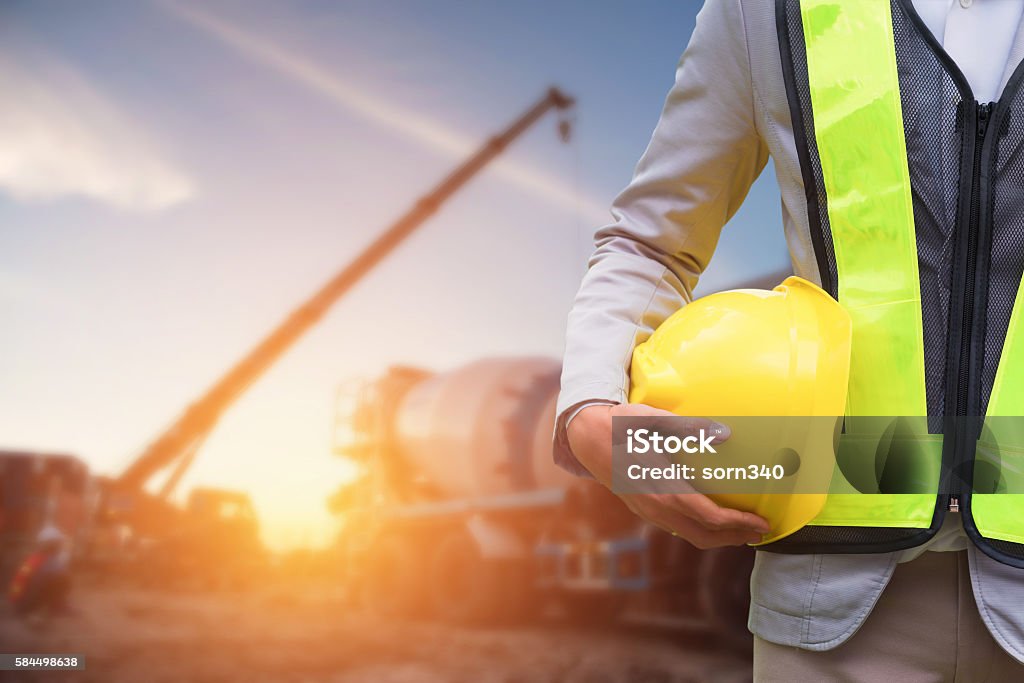 Engineer or Safety officer Engineer or Safety officer holding hard hat with the mobile crane machine is background in construction site. Education Training Class Stock Photo