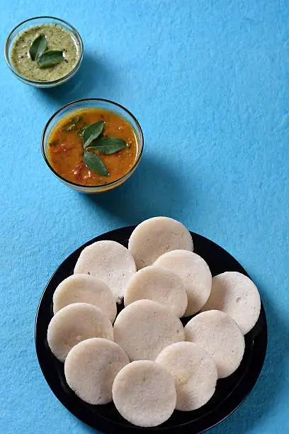 Photo of Idli with Sambar and coconut chutney on blue background