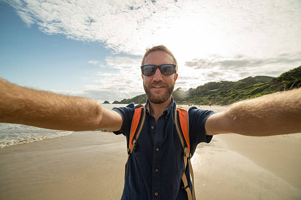 giovane in spiaggia scatta selfie ritratto usando action camera - australia photographing camera beach foto e immagini stock