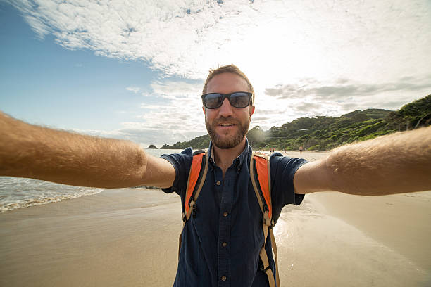 ビーチの若い男は、アクションカメラを使用して自分撮り肖像画を取ります - australia photographing camera beach ストックフォトと画像