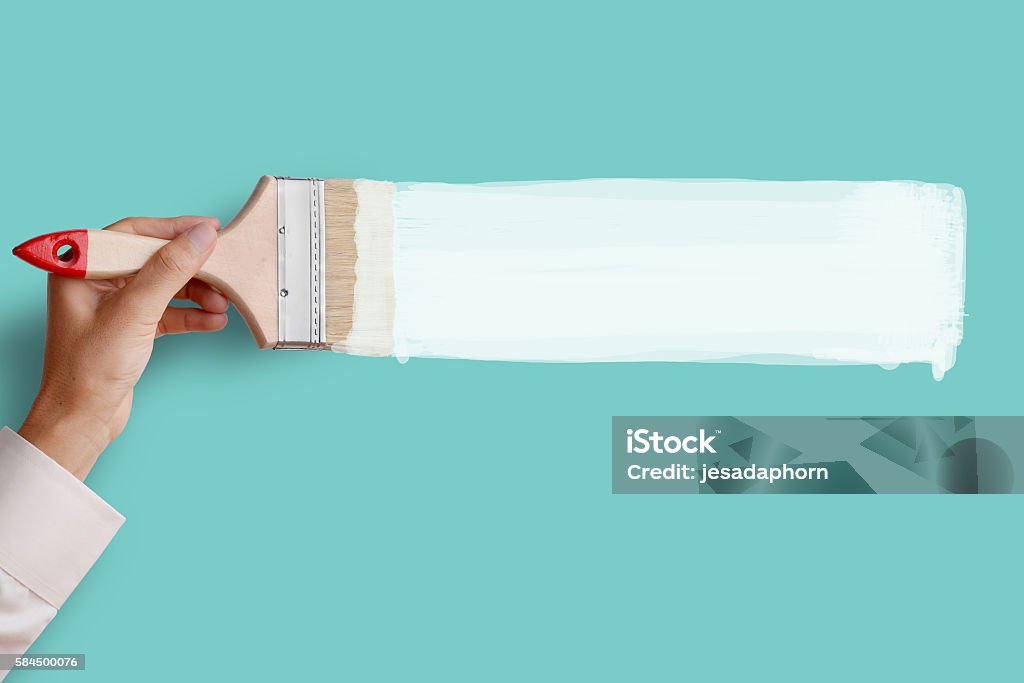 Paint white color on pink wall Man's hand holding paintbrush paint white color on blue aqua color wall, blank space for your text, banner, copyspace, advertising, or your design. Paintbrush Stock Photo