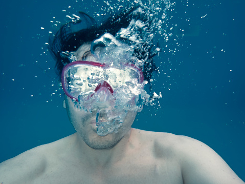 Man diving underwater wearing scuba mask
