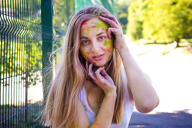 istock Blonde woman with colored powder on her face 584501416