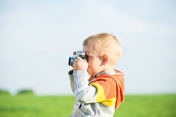 istock Little boy with an old camera shooting outdoor. 584501574