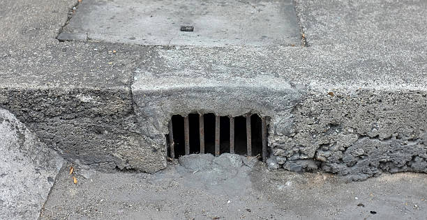istock Drain gutter in the road, next to pavement, showing curb 584503096