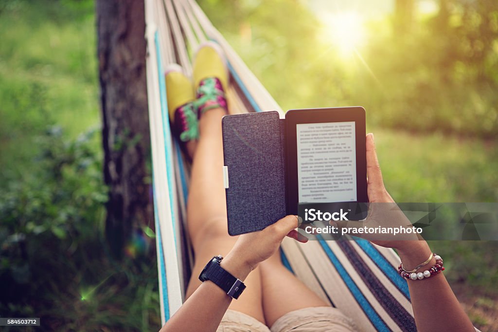 Beautiful girl is reading e-book in the hammock Beautiful girl is reading e-book in the hammock. E-Reader Stock Photo