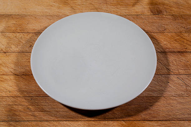istock Flat off white plate on wooden cutting board from side 584504254