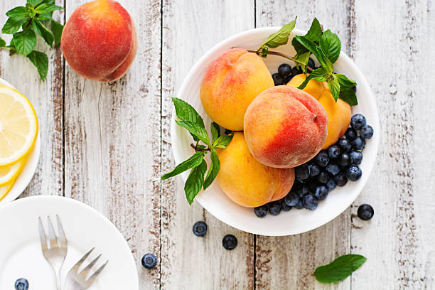 melocotones frescos y arándanos en bol - peach nectarine portion fruit fotografías e imágenes de stock