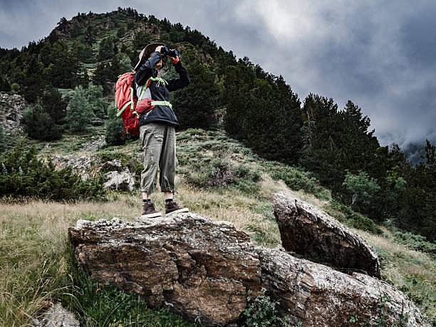 istock Woman looking through binoculars in the mountains 584505954