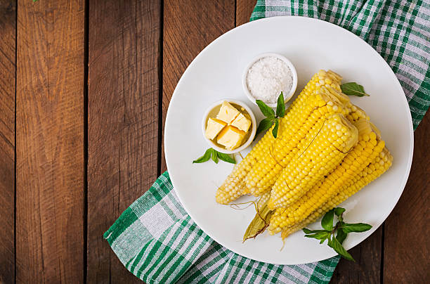 Boiled corn with salt and butter on a white plate stock photo