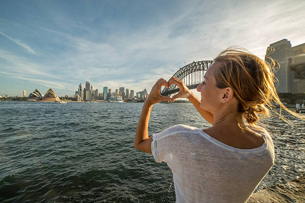 istock Woman makes heart shape finger frame on Sydney skyline 584511582