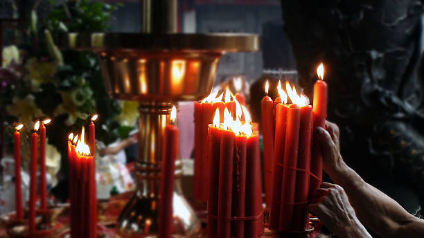 istock Scene Of Hand Pulling Up Lighted Red Candle In Temple 584511786