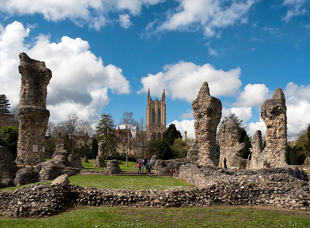 St Edmundsbury Cathedral and Abbey ruins Bury St Edmunds, Suffolk, England - April 17, 2016: People exploring the ruins of the former Bury St Edmunds Abbey, while on the right a man takes photographs of a woman. Bury St Edmunds is an ancient town, built around the Abbey which housed the shrine of King Edmund (St Edmund) and became a place of medieval pilgrimage. Today it is a popular place for tourists to explore and the Abbey Gardens, with the Abbey’s ruins, are extremely interesting. In the background is St Edmundsbury Cathedral, framed by the ruins. bury st edmunds stock pictures, royalty-free photos & images