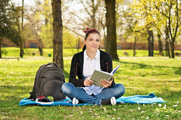 istock Female student in a park holding a book 584570092