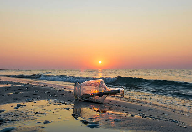 istock Message in a bottle on beach at sunrise 584573858