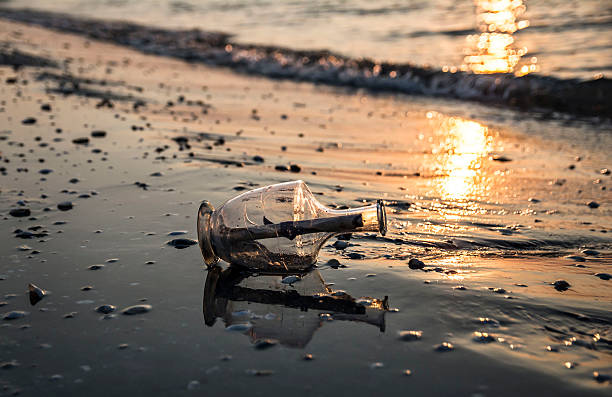 istock Message in a bottle on beach at sunrise 584573914