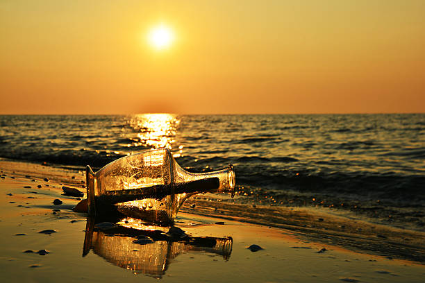 istock Message in a bottle on beach at sunrise 584574120