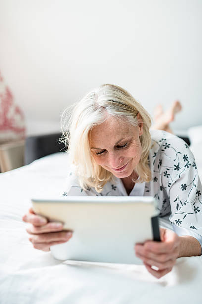 istock woman using the tablet lying down on the bed 584577900