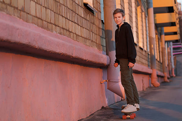 Skateboarding adolescente montando justo en la calle de la ciudad del atardecer - foto de stock