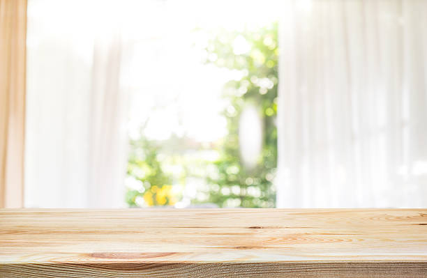 istock Wood table top on blur curtain window with green garden. 584580322