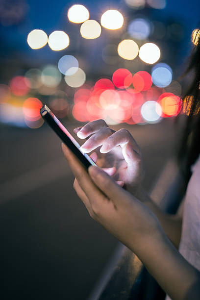 istock using mobile phone in the street at night 584580398