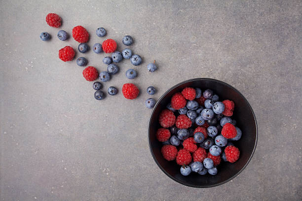 istock Blueberries and raspberries in a bowl on rusty grey background 584581404