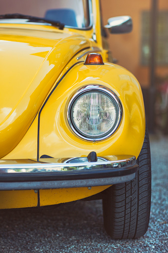 Sigtuna, Sweden - July 6, 2016: Front view of a yellow classic Volkswagen Beetle standing on parking lot. The beetle was produced by Volkswagen between 1938 and 2003.
