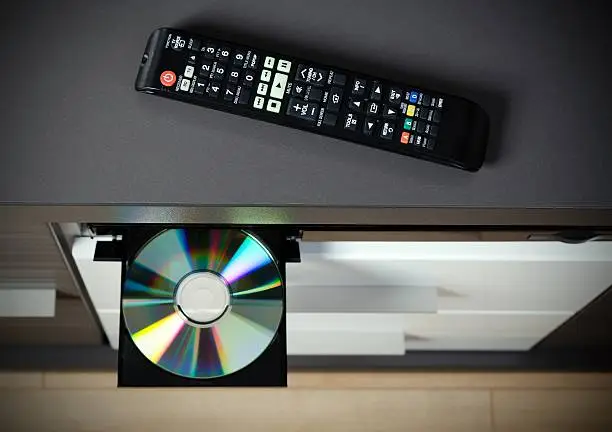 Remote control and Blu-ray or DVD player with inserted disc.