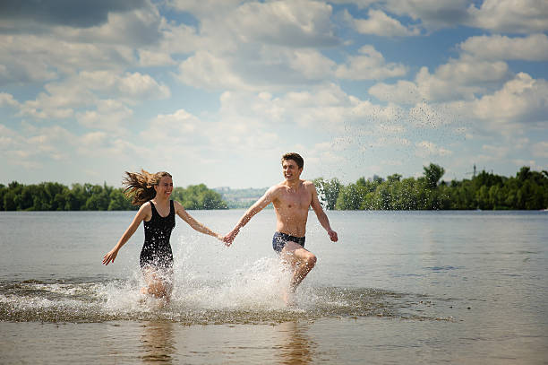 istock Young couple runs in water 584590346