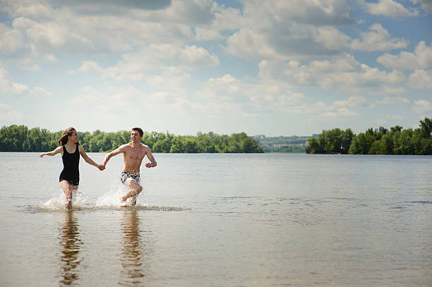 istock Young couple runs in water 584590374