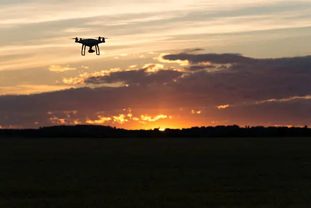 Photo of Drone silhouetted against orange sunset